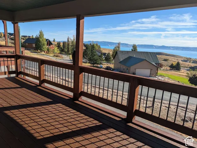 Expansive deck featuring wood-finish flooring, sturdy wood railings with dark balusters, and an overhead porch ceiling
