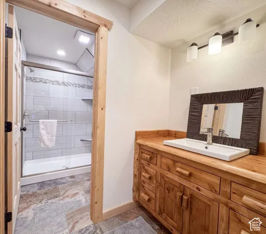 Wood vanity with a rectangular basin sink, wood-finish countertop, and wall-mounted light fixture