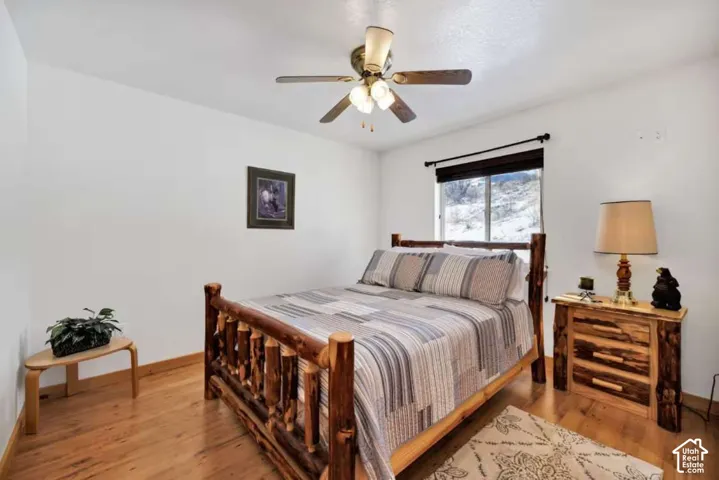Recessed window with black trim, wood-finish flooring, ceiling fan with integrated lighting, and white painted walls