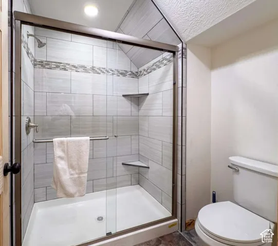 Enclosed shower with tiled walls, decorative tile accent band, and integrated corner shelves