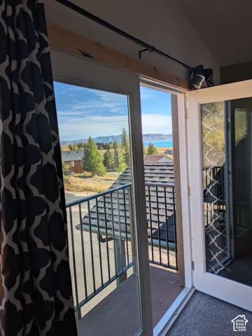 Glass panel doors opening to an exterior balcony with metal railings and a distant body of water