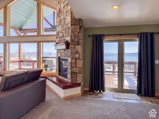 Stone-clad fireplace with wood mantel, large picture windows, wood-framed transom windows, sliding glass doors, and recessed lighting