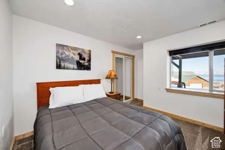 Recessed ceiling lighting, wood-finish trim, window with exterior scenery, sliding closet doors, and textured carpeting