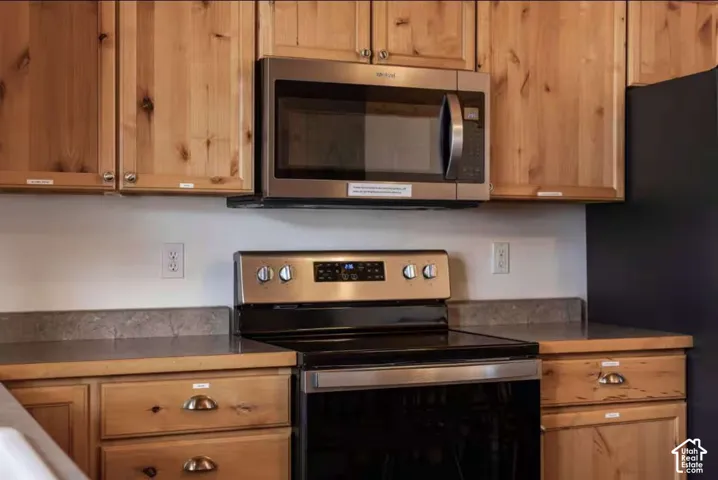 Stainless steel microwave and range, wood-finish cabinetry, and solid surface countertops