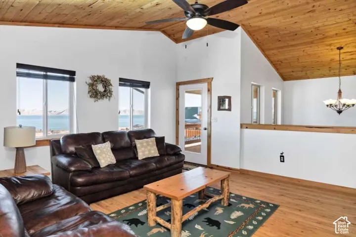 Vaulted wood-paneled ceiling, wood-finish flooring, ceiling fan with integrated lighting, glass-paneled door, and multiple windows