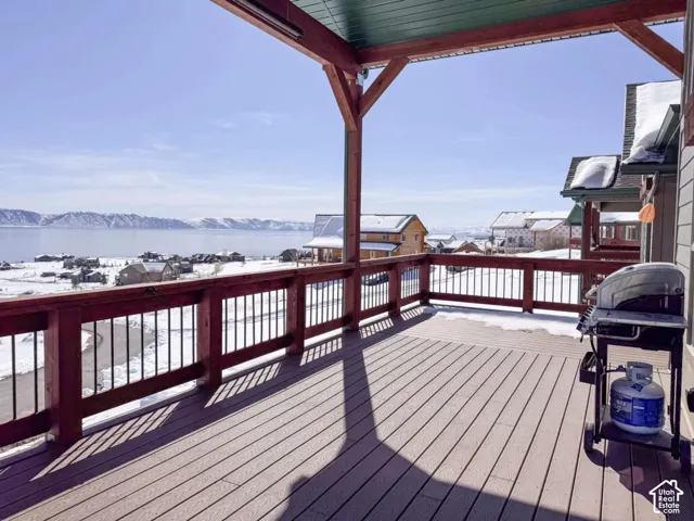 Covered outdoor deck with composite decking and wooden railings, offering expansive water and mountain scenery
