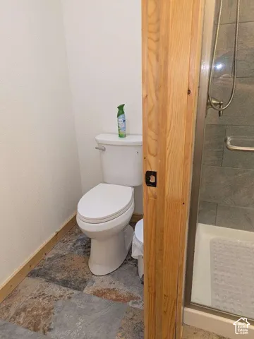 White toilet with a built-in shower featuring a glass enclosure