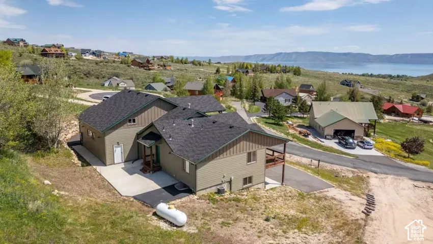 Exterior featuring a multi-level design, attached garage, dark shingle roofing, and light-colored siding