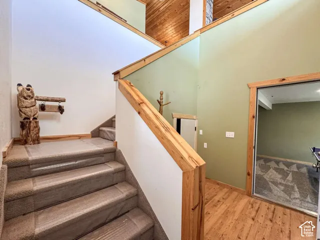 Wood-finish flooring, staircase with carpeted treads, and wood-trimmed doorways