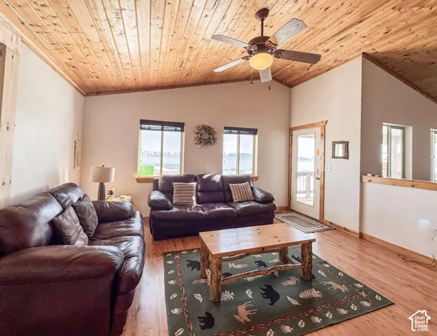 Vaulted ceiling with wood paneling, wood-finish flooring, ceiling fan with integrated lighting, two windows, and a glass-paneled exterior door