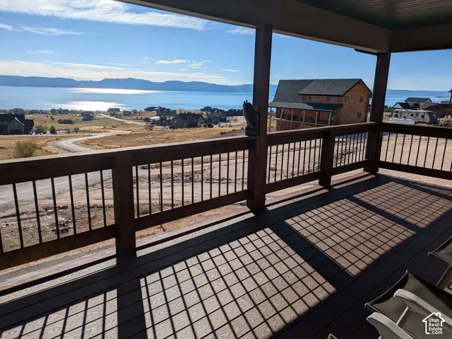 Covered outdoor deck with composite decking, dark wood railing, and metal balusters