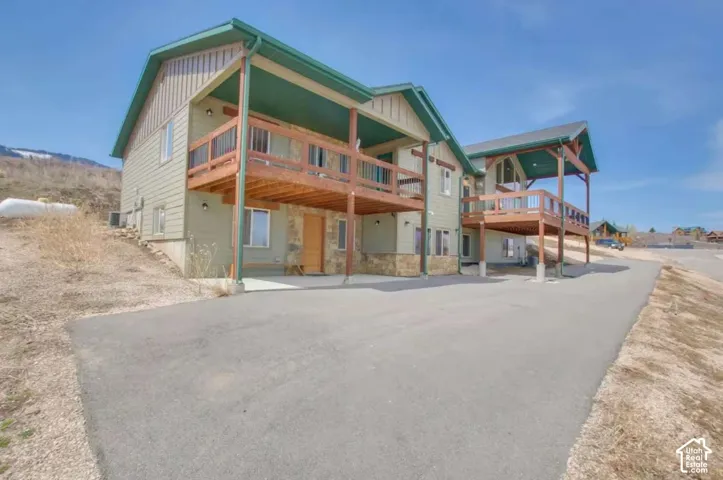 Siding exterior with stone accents, covered balconies with wood railings, and an asphalt driveway