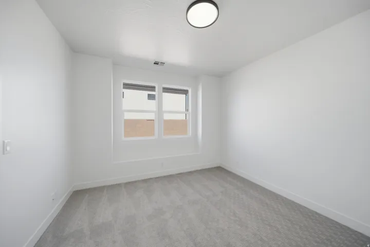 Recessed window alcove with two horizontal windows, light gray patterned carpeting, and a flush-mount ceiling light fixture
