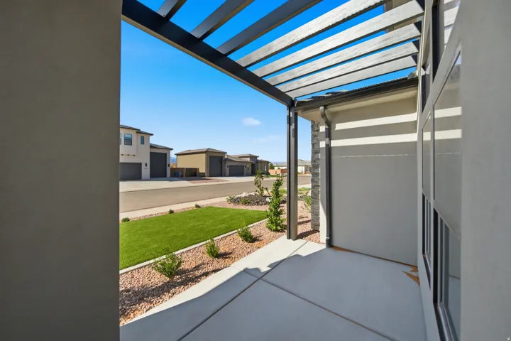 Private patio with a modern pergola, concrete flooring, stucco exterior, and stone accent column