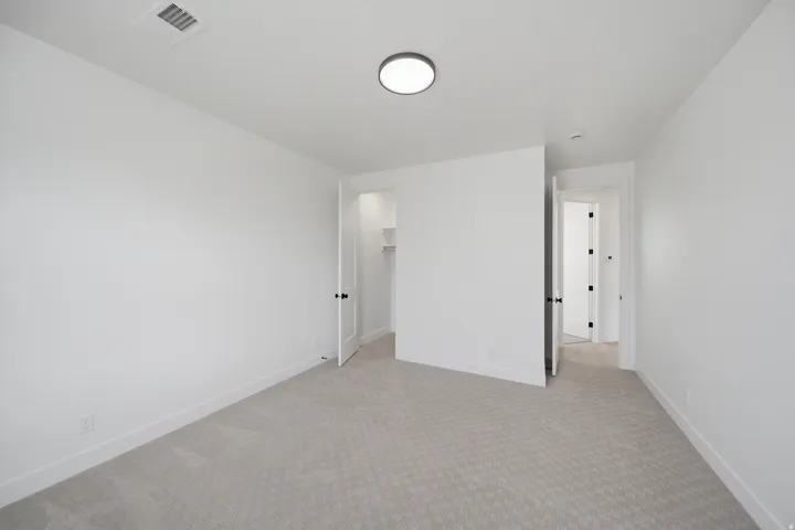 Neutral wall color, patterned carpet flooring, recessed ceiling lighting, and solid core doors with dark hardware