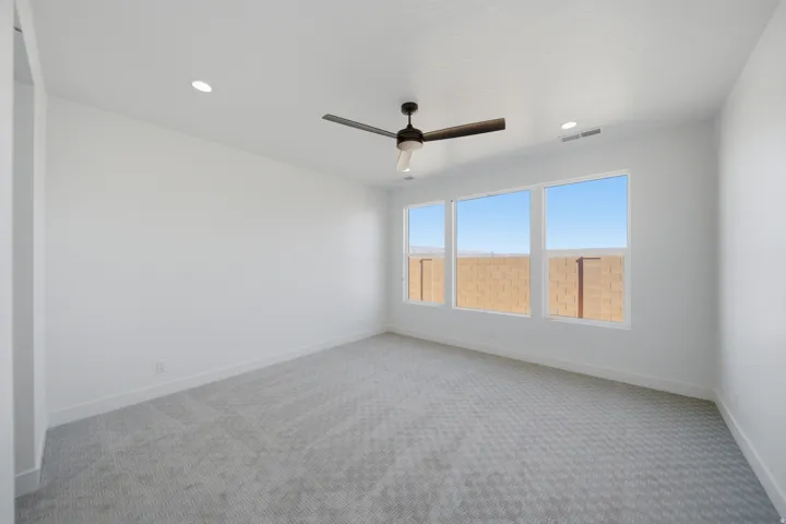 Recessed lighting, ceiling fan, and light-toned patterned carpeting