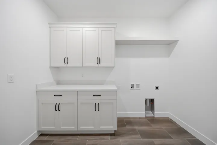 White cabinetry with matte black hardware, stone-finish countertops, tiled flooring, and a built-in recessed shelf