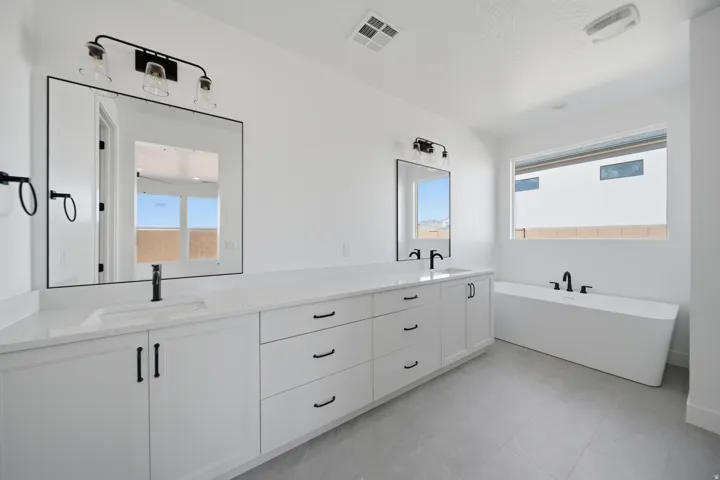 Dual vanity with white cabinetry, matte black hardware, and integrated sinks