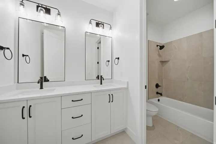 Dual vanity with rectangular undermount sinks, white cabinetry, and matte black hardware