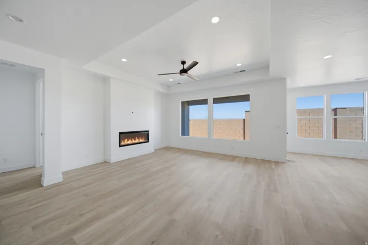 Spacious living area featuring wood-finish flooring, an electric fireplace, a ceiling fan, recessed lighting, and large windows