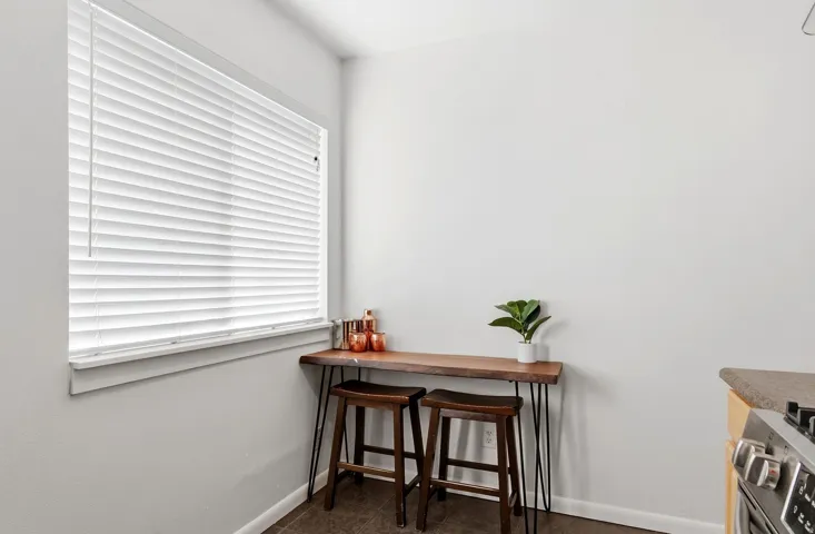 White window blinds with a sill, light-toned wall paint, and dark tile flooring