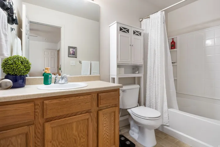Bathroom featuring a vanity with wood-finish cabinetry, a single basin sink, and a light-toned countertop