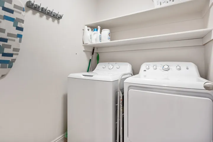Laundry area featuring a top-load washing machine, front-load dryer, and two built-in shelves