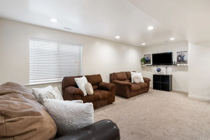 Recessed ceiling lighting, neutral wall finishes, a window with horizontal blinds, and carpeting