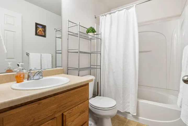 Vanity with wood-finish cabinetry, integrated sink, and light-toned countertop