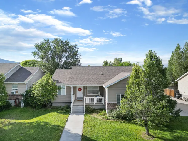 Single-level residence featuring a covered front porch with white railings, a concrete walkway, and an attached two-car garage