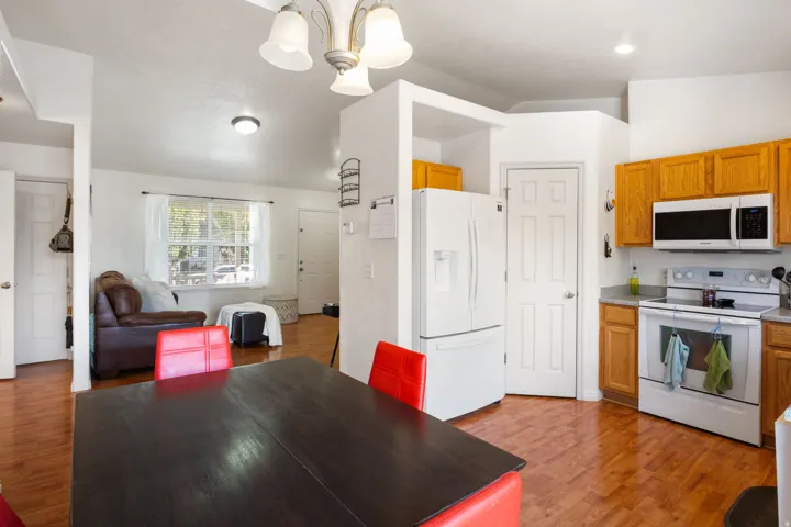 Kitchen with laminate flooring, oak cabinetry, white appliances, and a built-in microwave