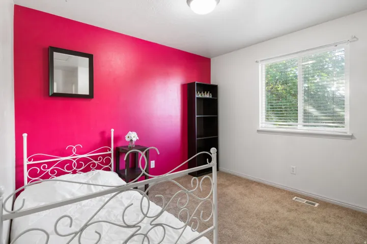 Carpeted room featuring a single window with blinds, a built-in shelf unit, and a ceiling-mounted light fixture