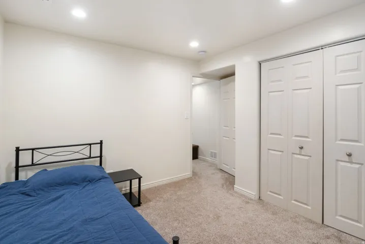 Recessed ceiling lighting, white walls, light-colored carpeting, white bi-fold closet doors, and white trim throughout