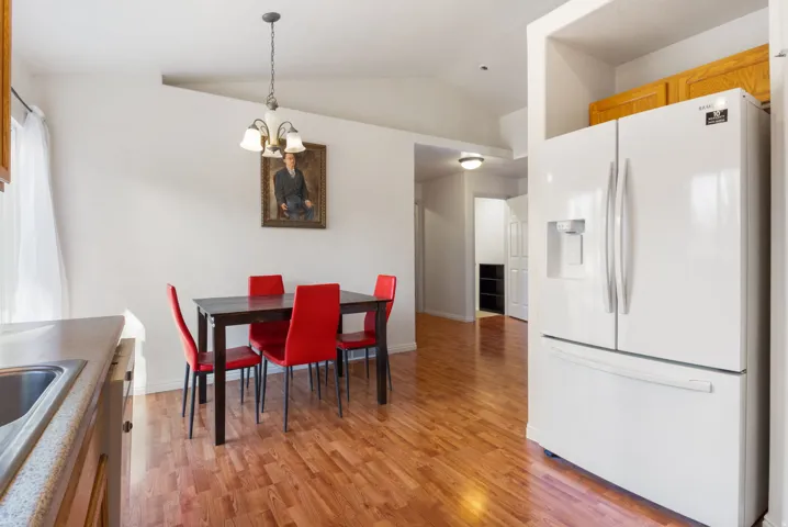 Vaulted ceiling, laminate flooring, recessed lighting, built-in cabinetry, and integrated refrigerator