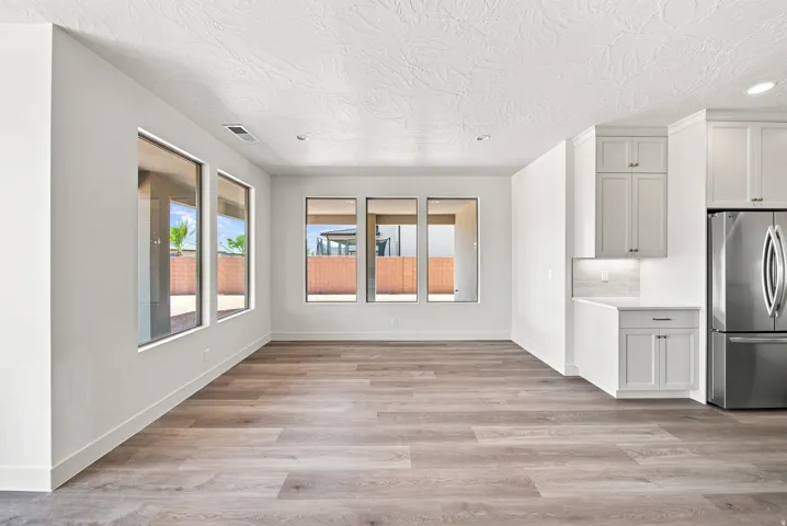 Open-concept living area featuring wood-finish flooring, recessed lighting, expansive windows, light-toned cabinetry, and stainless steel appliances