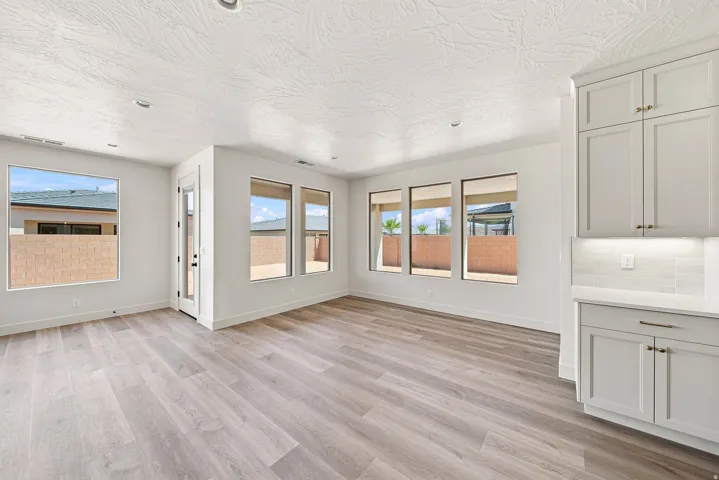 Wood-finish flooring, white cabinetry, light-toned countertops, tiled backsplash, and recessed lighting