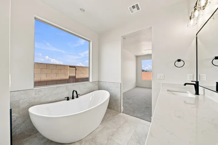 Freestanding soaking tub with matte black fixtures, set against a tiled wall