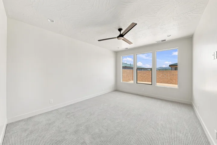 Neutral-toned walls, textured ceiling, recessed lighting, ceiling fan with wood-finish blades, and three large windows