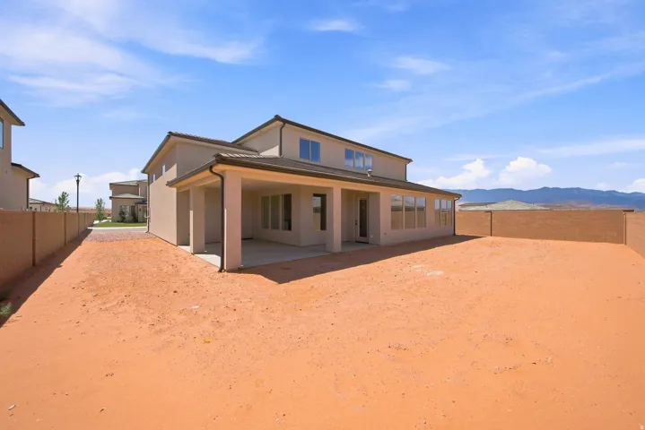 Two-story stucco exterior with a covered patio and a large backyard area