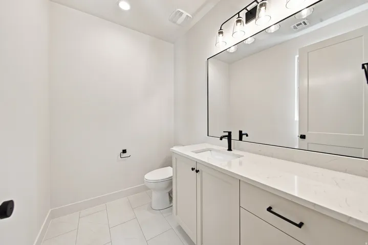 White vanity with an integrated sink, black hardware, and a stone countertop
