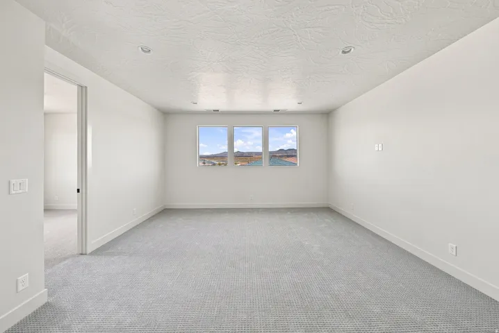 Recessed lighting illuminates the neutral-toned carpeted flooring and white walls