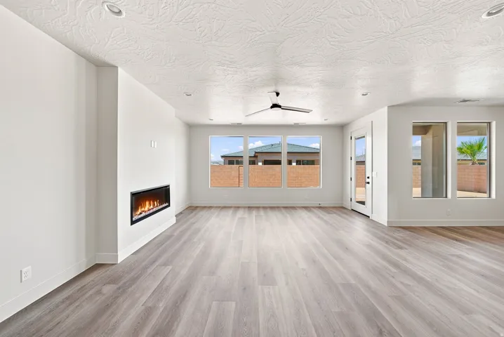 Spacious room featuring wood-finish flooring, a built-in linear electric fireplace, recessed lighting, and a ceiling fan