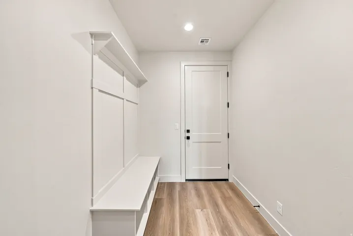 Built-in hall tree with integrated bench and upper shelving, wood-finish flooring, recessed lighting, and a paneled interior door with matte black hardware
