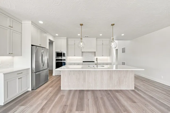 Spacious kitchen with a wood-finish island, stainless steel appliances, recessed and pendant lighting, and light-toned cabinetry