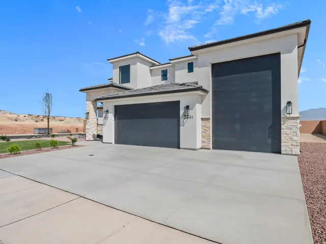 Contemporary exterior with stucco finish, stone accents, two large garage doors, and a spacious concrete driveway
