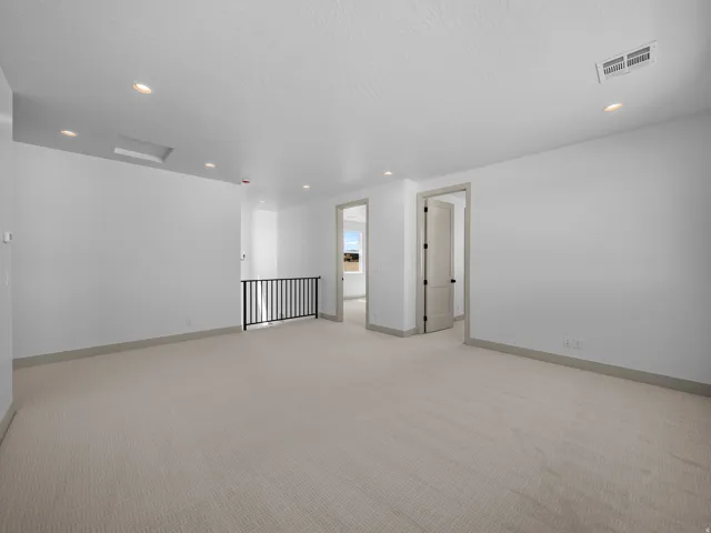 Spacious carpeted area with recessed lighting, a skylight, and a metal railing