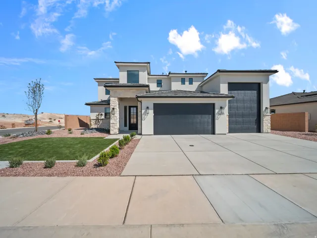 Modern stucco exterior with stone accents, multiple garage doors, a concrete driveway, and landscaped front yard