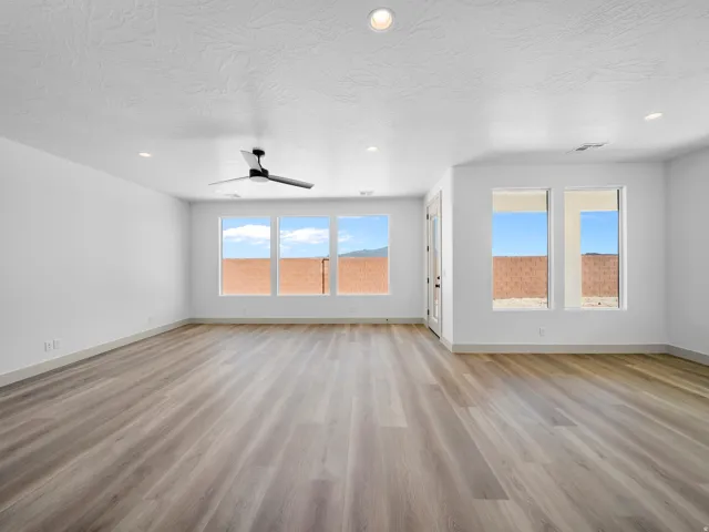 Expansive room featuring wood-finish flooring, recessed lighting, and a modern ceiling fan