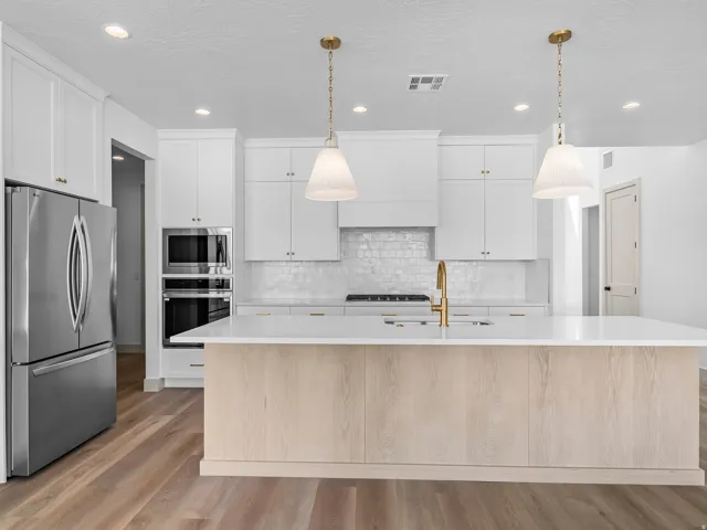 Modern kitchen featuring white cabinetry, a large center island with light wood-finish paneling, stainless steel appliances, recessed lighting, and wood-finish flooring