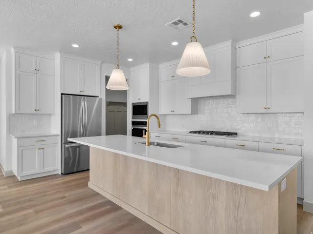 Kitchen featuring white shaker cabinetry, stainless steel appliances, a center island with a light wood-finish base and white countertop, a gas range with an overhead hood, and wood-finish flooring